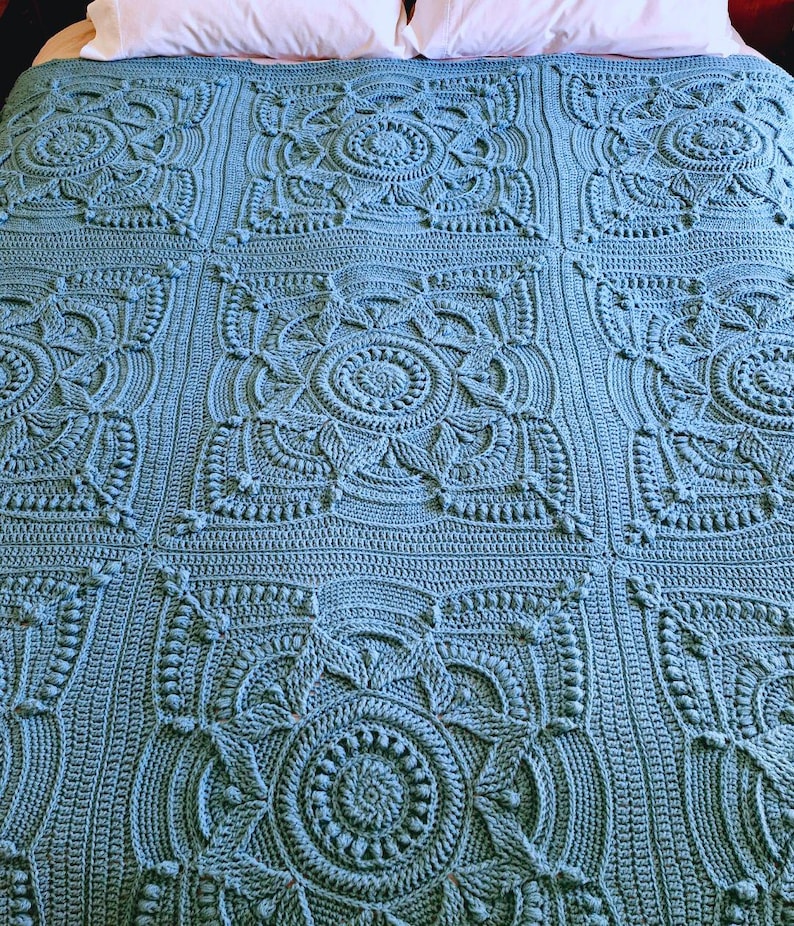 Crochet blanket laying on queen-sized bed.