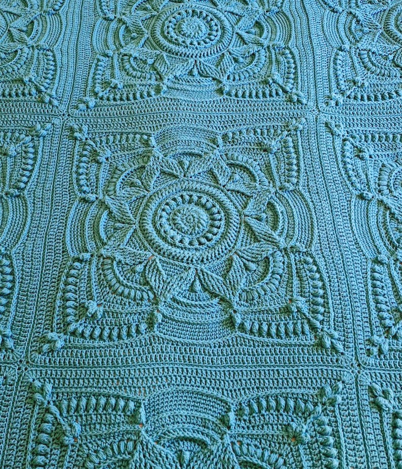 Crochet blanket laying on queen-sized bed.