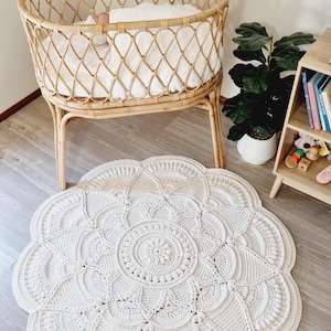 Floral, white crochet floor rug in front of a baby bassinet.