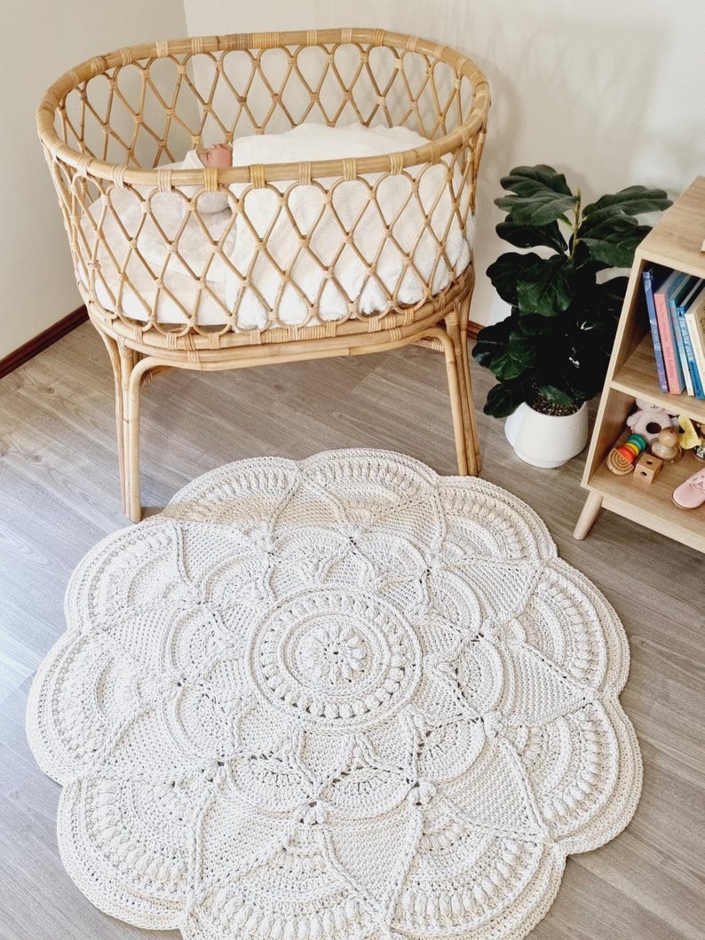Floral, white crochet floor rug in front of a baby bassinet.