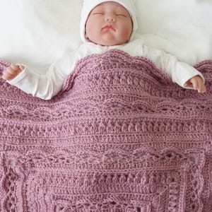 Baby in bed with a crochet blanket.