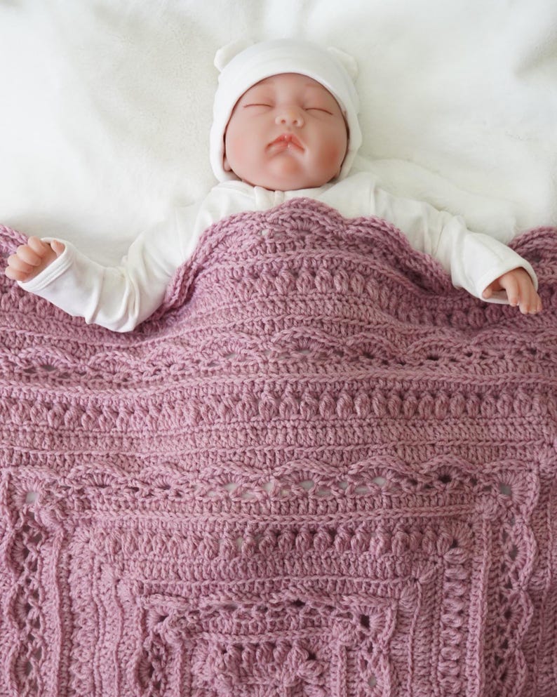 Baby in bed with a crochet blanket.