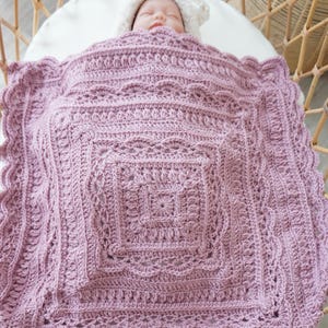 Pink crochet baby blanket in a bassinet.