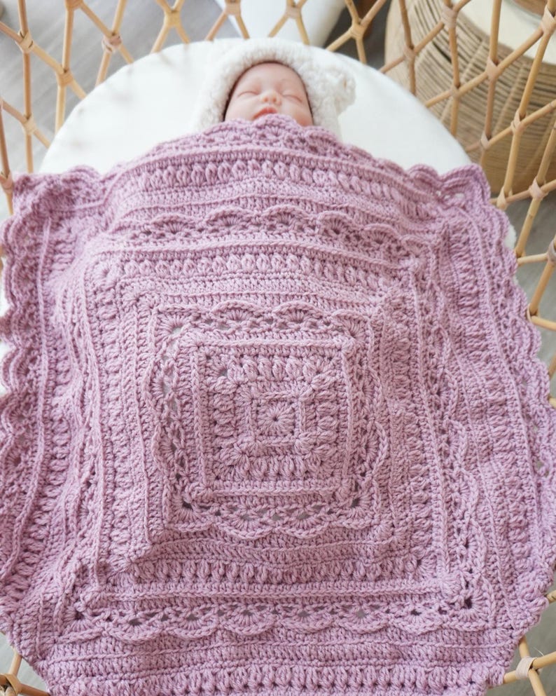 Pink crochet baby blanket in a bassinet.