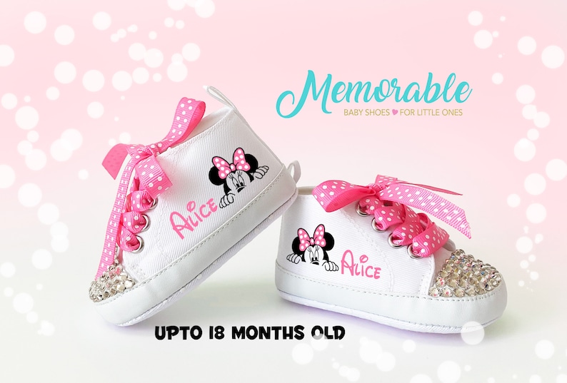 May include: White baby shoes with pink polka dot laces and a Minnie Mouse graphic. The shoes have a rhinestone-studded toe and the name "Alice" printed on the side. The text "Memorable BABY SHOES FOR LITTLE ONES" and "UPTO 18 MONTHS OLD" are also visible.