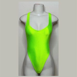 May include: A bright neon green one-piece swimsuit with a scoop neck and a high leg cut.