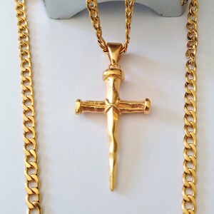 May include: A gold chain necklace with a gold cross pendant. The cross is a simple design with a textured, hammered finish.