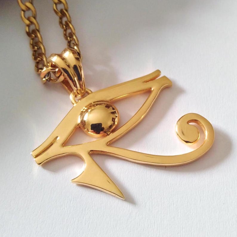 May include: A gold-tone pendant necklace featuring the Eye of Horus, an ancient Egyptian symbol of protection and good health.