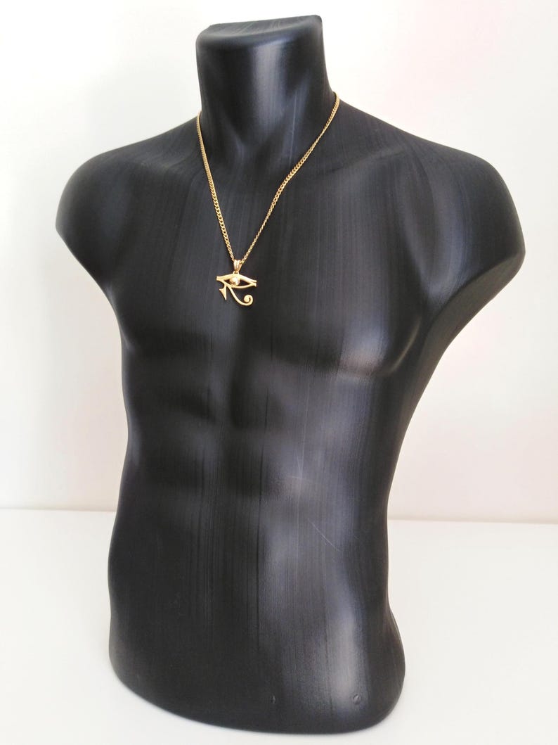 May include: A gold chain necklace with a gold pendant featuring the Eye of Horus symbol.