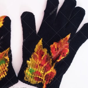 Puede incluir: Guantes de punto negros con un dise&ntilde;o pintado de hojas de oto&ntilde;o en tonos rojos, naranjas, amarillos y verdes. Los guantes tienen un patr&oacute;n de punto texturizado.