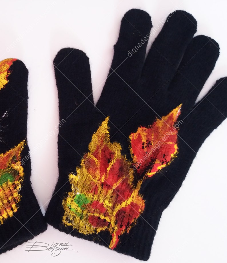 Puede incluir: Guantes de punto negros con un dise&ntilde;o pintado de hojas de oto&ntilde;o en tonos rojos, naranjas, amarillos y verdes. Los guantes tienen un patr&oacute;n de punto texturizado.