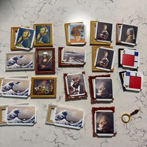 May include: A collection of miniature framed art prints featuring famous paintings. The prints include images of Van Gogh, the Mona Lisa, and Hokusai's Great Wave. The frames are gold, brown, and silver.