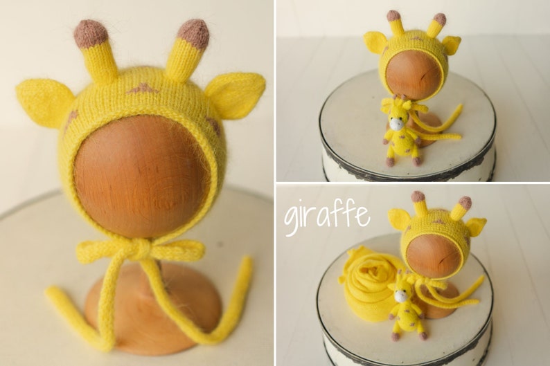 May include: A yellow knit bonnet featuring giraffe ears and brown-tipped horns, accompanied by a small matching giraffe plush toy. The set includes a yellow fabric wrap, and the word giraffe is written in white script text on the image.