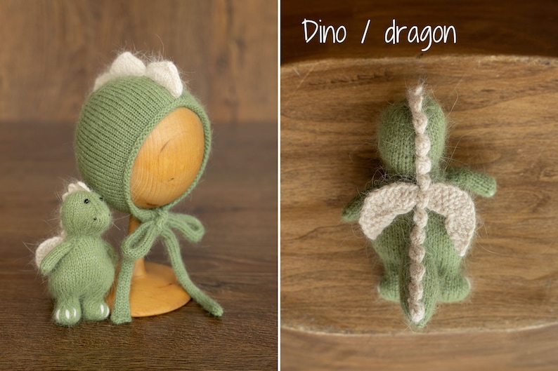 May include: A sage green knitted bonnet with a row of cream-colored spikes along the top and matching ties, accompanied by a small, matching sage green knitted dinosaur or dragon toy featuring cream-colored wings and a spiked back.