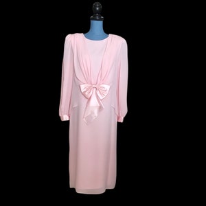 May include: A long-sleeved pink dress with a large satin bow at the waist.