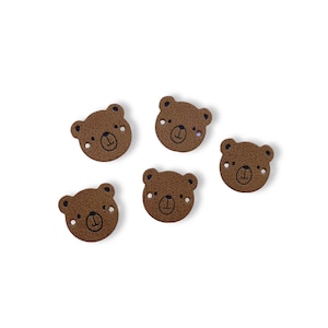 Könnte beinhalten: Fünf braune Leder-Bärenkopf-Patches mit schwarzen gestickten Augen und Nasen.
