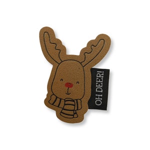 Op de afbeelding: Bruine leren rendier applique met een zwart-wit gestreepte sjaal en een rode neus. De applique heeft de tekst "OH DEER!" op een zwart label.