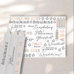 Könnte beinhalten: Ein weißes Blatt Papier mit bunten Stickern, auf denen der Text "Schulkind 2025" und andere verwandte Sätze in deutscher Sprache stehen. Die Sticker sind mit Sternen, Bleistiften und anderen schulbezogenen Bildern verziert.