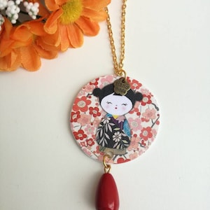 Collana lunga con ciondolo a cerchio di carta e immagine di bambolina kokeshi giapponese e pietra a goccia rossa.