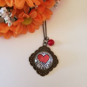 Keith Haring collana lunga con ciondolo a cerchio, immagine dedicata alla splendida arte di keith haring e perlina rossa