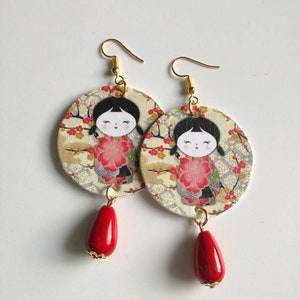 Paper earrings with pendant in the shape of a circle and Japanese image with red asymmetrical stones.