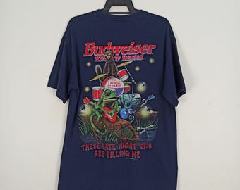 May include: Navy blue t-shirt featuring a graphic of a band of amphibians playing instruments. The text "Budweiser King of Beers" is above the band, and "These Late Night Gigs Are Killing Me" is below.