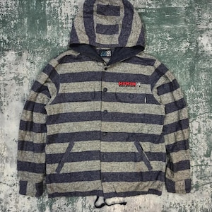 May include: A long-sleeve hooded shirt featuring horizontal stripes in heather gray and dark blue. The garment has a button-down front, two chest pockets, and a drawstring at the hem. The text MXMXM is embroidered in red on the left chest area.