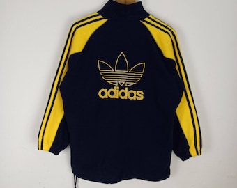 May include: A navy blue fleece jacket with yellow stripes and a large embroidered adidas logo on the back.