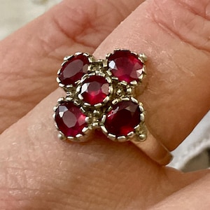Peut inclure: Une bague en argent avec cinq pierres précieuses rouges serties en forme de grappe.