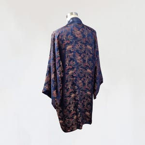 May include: A navy blue silk robe with a floral and bird pattern. The robe has a long, flowing silhouette and a wide collar.