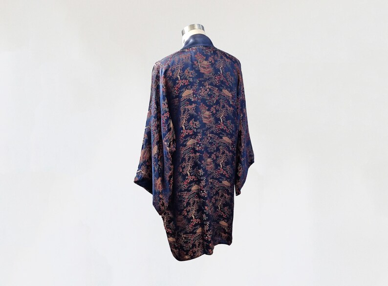 May include: A navy blue silk robe with a floral and bird pattern. The robe has a long, flowing silhouette and a wide collar.