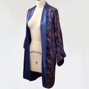 May include: A navy blue and pink patterned silk robe with a satin trim. The robe is open and draped over a dress form.