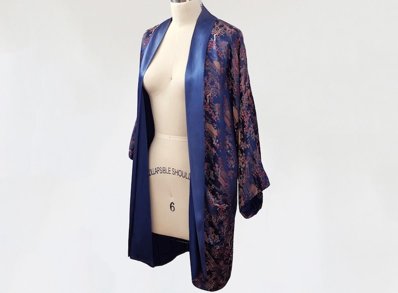May include: A navy blue and pink patterned silk robe with a satin trim. The robe is open and draped over a dress form.