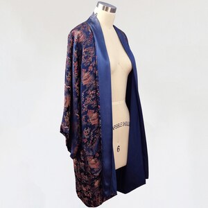 May include: A navy blue and gold patterned kimono robe with a satin lining. The robe is open in the front and has long sleeves.