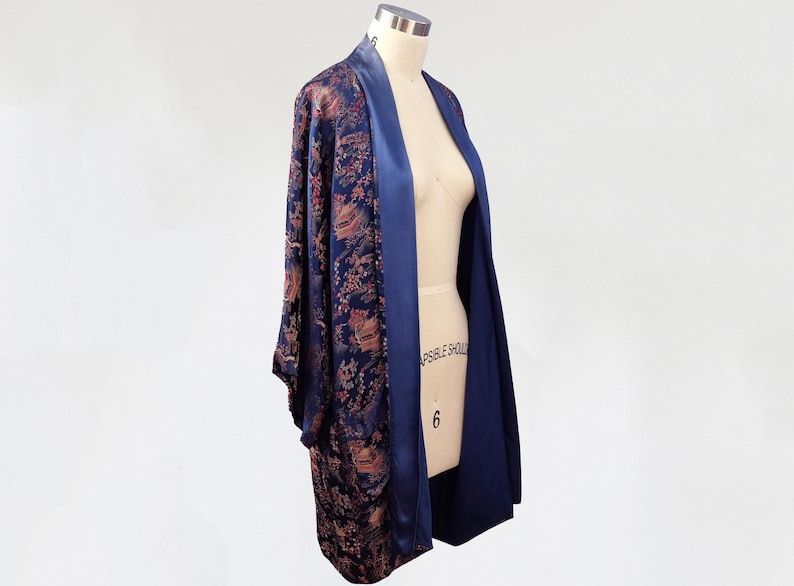 May include: A navy blue and gold patterned kimono robe with a satin lining. The robe is open in the front and has long sleeves.