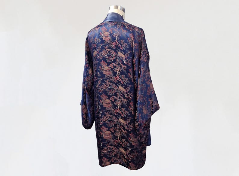 May include: A navy blue silk robe with a floral pattern in shades of pink and gold. The robe has long sleeves and a wide collar.