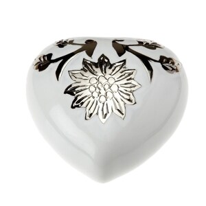 May include: White ceramic heart-shaped trinket box with a silver floral design.
