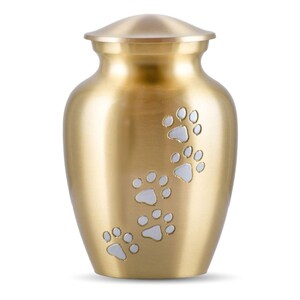 May include: Gold metal urn with white paw prints engraved on the side. The urn is a traditional shape with a lid.