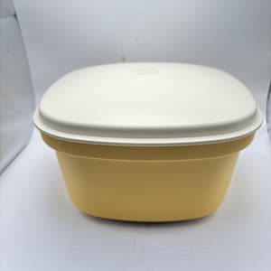 以下が含まれることがあります： 白い蓋が付いた、ヴィンテージの黄色のプラスチック容器。容器は角が丸い長方形です。蓋は上部にぴったりとフィットし、密閉性を高めています。容器はおそらく食品の保管に使用されます。