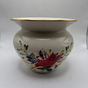 Peut inclure: Bol en céramique crème avec un bord doré. Le bol présente une illustration détaillée d'un cardinal rouge entouré de houx et de baies. Le design est festif et adapté à la décoration des fêtes.