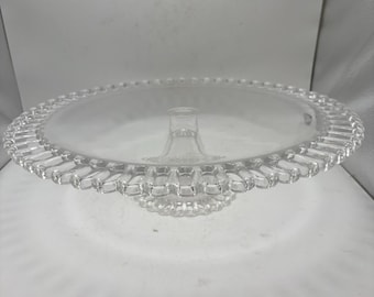 Soporte vintage para tartas de cristal transparente con diseño de encaje en el borde y la base.