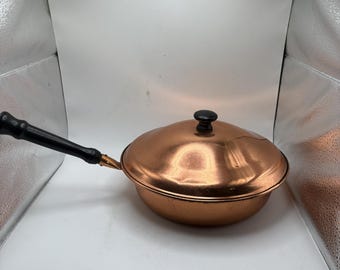 Olla de cobre vintage con mango y tapa de madera, utensilios de cocina rústicos.