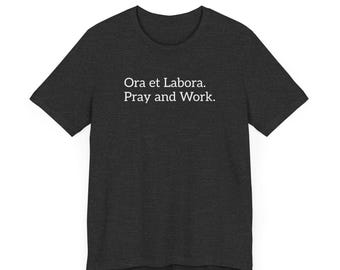 May include: A dark heather grey t-shirt with the text "Ora et Labora. Pray and Work." printed in white.