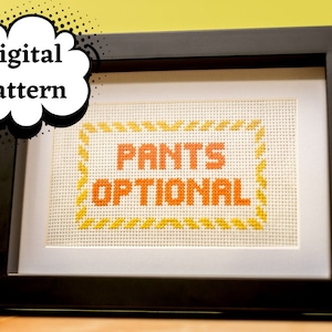 May include: A framed cross-stitch with the text "PANTS OPTIONAL" in orange letters on a white background. The frame is black and the background is yellow.