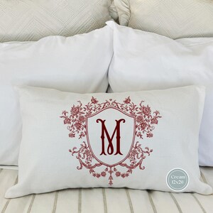 May include: White pillow with a red embroidered monogram "M" in a decorative floral frame. The pillow is 12x20 inches.
