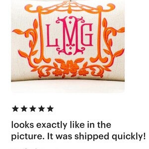 May include: A white pillow with an orange and pink monogram design. The monogram is "LMG" in a decorative font. The pillow has a floral design around the monogram.