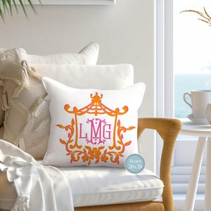 May include: A white pillow with a monogram design featuring the letters LMG in pink. The monogram is surrounded by an orange floral design. The pillow is 20x20 inches and is labeled "Ivory".