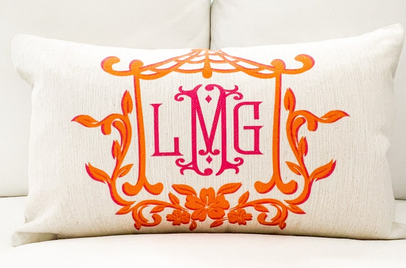 May include: A white pillow with an orange and pink monogram design. The monogram is "LMG" in a decorative font. The design features floral elements and a decorative frame.