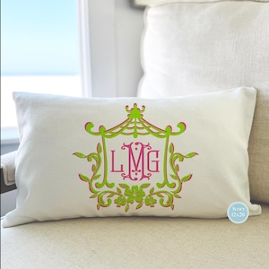 May include: A white pillow with a green and pink monogram design. The monogram is "LMG" and is surrounded by a decorative frame. The pillow is 12x20 inches.