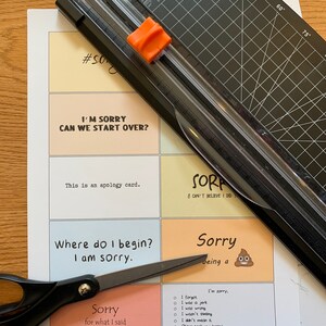 Peut inclure: Un ensemble de cartes d'excuses avec diff&eacute;rents messages et illustrations. Les cartes sont imprim&eacute;es sur du papier color&eacute; et ont une bordure blanche. Les cartes sont dispos&eacute;es en grille sur une table. Le texte sur les cartes comprend : "Je suis d&eacute;sol&eacute;, on peut recommencer ?", "C'est une carte d'excuses.", "Par o&ugrave; commencer ? Je suis d&eacute;sol&eacute;.", "D&eacute;sol&eacute; pour ce que j'ai dit quand j'avais faim.", "D&eacute;sol&eacute; d'&ecirc;tre un caca emoji", et "Je suis d&eacute;sol&eacute;, j'ai oubli&eacute;, j'&eacute;tais un cr&eacute;tin, j'avais tort, je ne pensais pas, je ne le pense pas, Les autres ont pris mon cerveau, Folie passag&egrave;re."